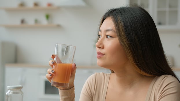 Korean woman drinking fresh smoothie orange juice. Asian vegetarian girl tasting glass of vitamin fruity cocktail peach drink healthy diet weight loss healthcare nourishment morning detox in kitchen photo