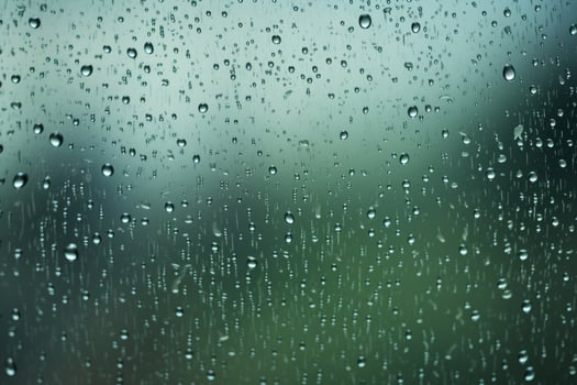 Shiny raindrops splashes falling cascading down wet glossy foggy glass window car outdoor during rainy stormy day backdrop. Close-up processes motion of beautiful clear fresh water photo