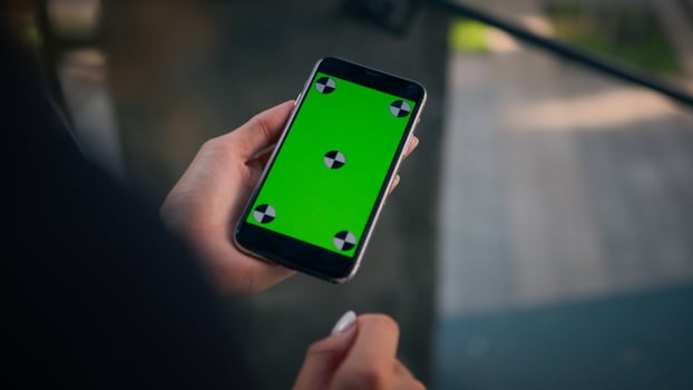 Rear over shoulder view businesswoman using smartphone green screen chroma key mobile mockup unknown girl woman hold phone with copy space cellphone device business app online order in city outdoors photo