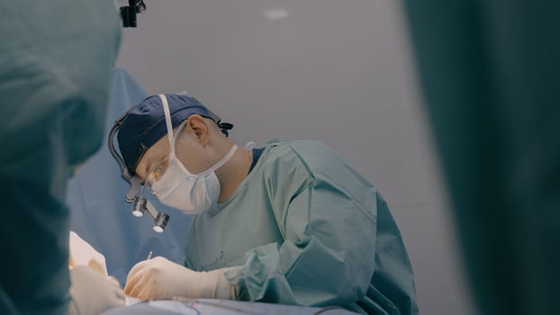 Surgeon man practitioner with team assistants perform surgical operation doctor sewing up wound sutures skin with medical tools clips thread in hospital operating room patient health treatment surgery photo