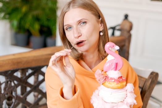 Happy woman eating sweet dessert in form pink flamingo in restaurant, woman photo