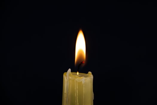 Single burning candle over black background photo