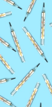 Mercury-in-glass thermometer creative pattern on blue background flat lay healthcare, treatment concept vertical photo
