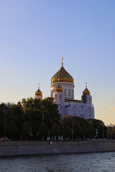 The beautiful white Russian orthodox church with golden domes on the river in Moscow at sunset. photo