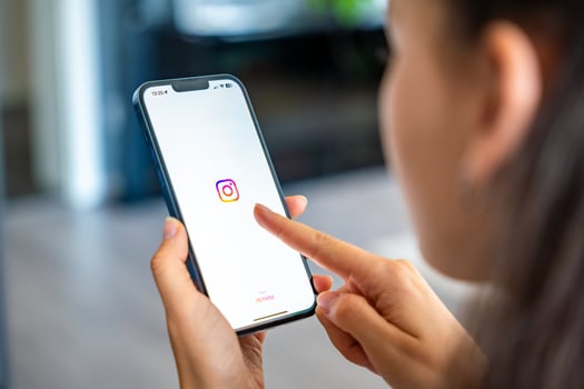 Prague, Czech republic - May 2, 2024. Woman holding iPhone with streaming photo and Instagram on the screen, using mobile application at home. High quality photo