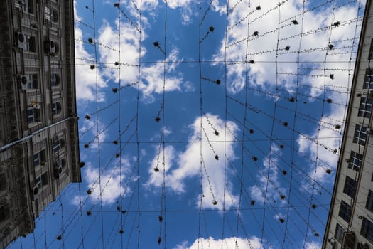 Many little hanging lanterns against a blue sky and white clouds photographed from below. photo