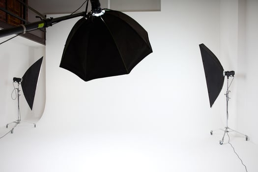 photo studio inside, white background, several racks with light sources, cyclorama, softboxes, pulsed light, flashes