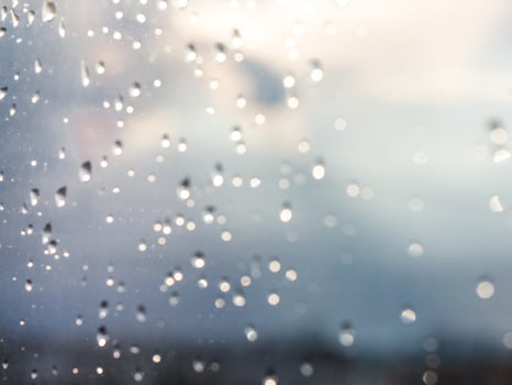 Blurred water drops of rain on blue glass with bokhe as background. Blurred rain drops on window photo