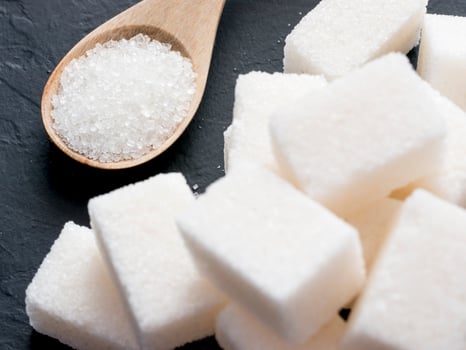 background of sugar cubes and sugar in spoon. White sugar on black background. Sugar cubes and granulated in wooden spoon photo