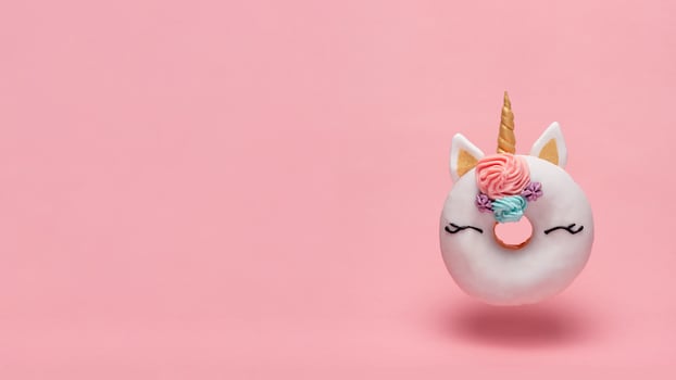 Unicorn donut flying, pink background, copy space photo