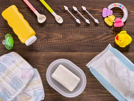 Baby essentials and care on dark wooden table with copyspace photo