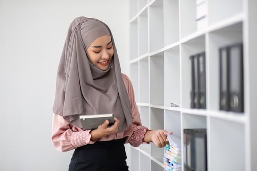 Smiling Muslim business woman Wearing a hijab while chatting online on a work desk in the office. photo