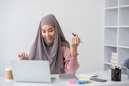 Smiling Muslim business woman Wearing a hijab while chatting online on a work desk in the office. photo