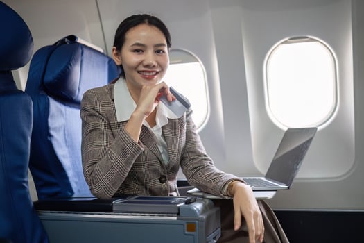 Young Asian woman holding credit card shopping online using website on laptop Sitting near window in first class on airplane during flight, travel and business concept. photo