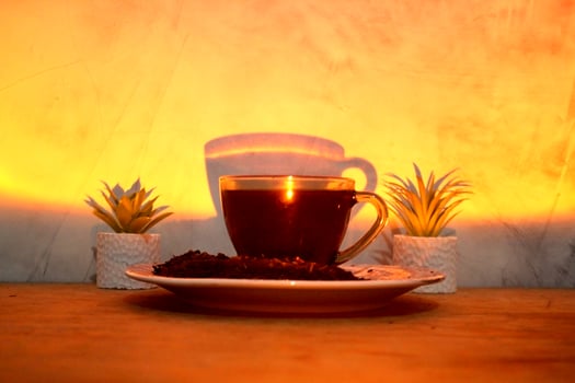 A hot tea served in a cup and placed on a table with a bright yellow lamp. photo