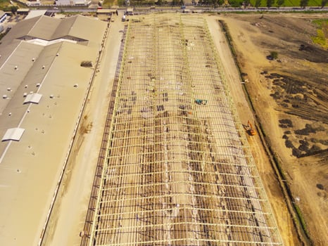 Factory under construction. Aerial drone photo of a factory being built by workers on the edge of Bandung City. Top view of Factory construction