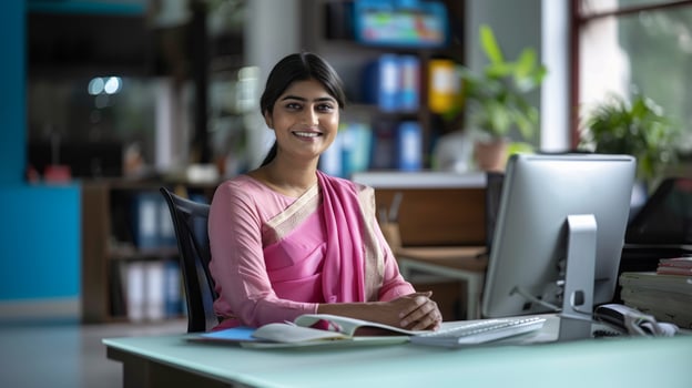 Cheerful young Indian businesswoman sitting at her workplace photo