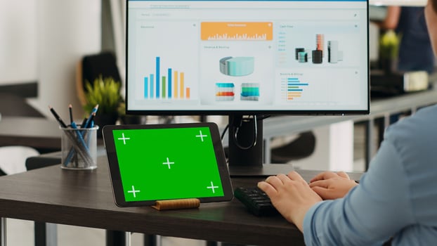 Specialist having greenscreen on tablet and typing e commerce information on computer at office desk, working on increasing small company budget. Startup manager looks at isolated chromakey layout. photo