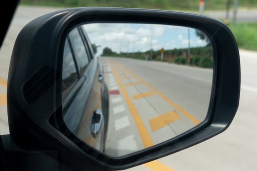 Abstract mirror wing of car. Looking back for trip yellow line in center of road. Under blue sky in the day time. Traffic is empty, there are no cars on the road. photo