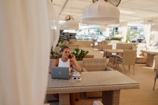 Woman coffee cafe macbook. Woman sitting at a coffee shop with mobile phone drinking coffee and looking away. Caucasian female relaxing at a cafe. photo
