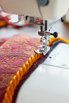 sewing machine. the process of sewing a decorative cord of red fabric. photo