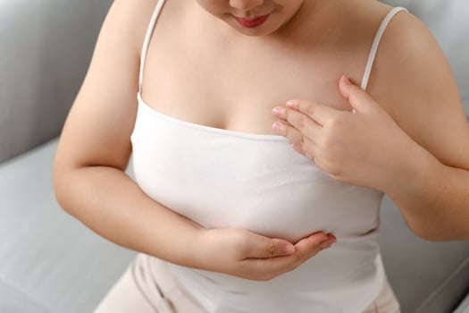 Asian woman checking lumps on her breast for signs of breast cancer by her self at home photo
