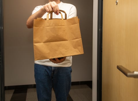 courier holds paper bag and phone with white blank screen and inscription, order delivery concept, online shopping photo