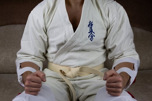 Kyokushinkai karate athlete with white belt and special protective equipment and kimano sits before the competition photo