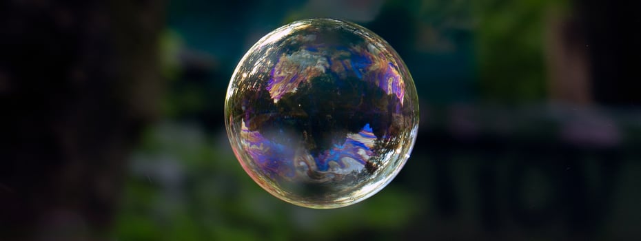 perfectly round soap bubble of a blue hue, with solar reflection and shimmer of light against a dark background photo