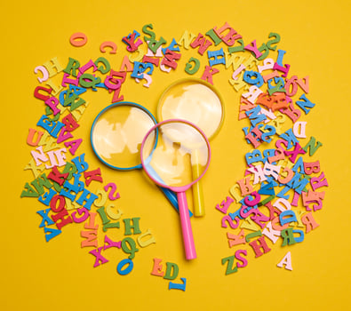 Plastic magnifying glass and wooden letters of the English alphabet on a yellow background photo