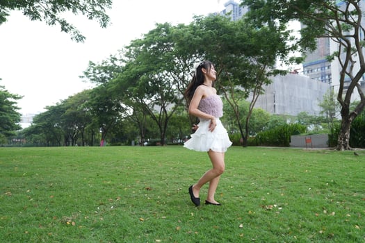 calm indoor area, a woman dances freely near a decorative brick wall and lush plants, radiating freedom and energy. photo