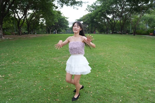 In a calm i ndoor area, a woman dances freely near a decorative brick wall and lush plants, radiating freedom and energy. photo