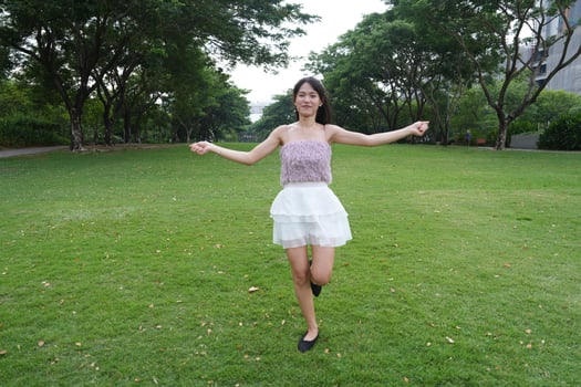 In a calm indoo r area, a woman dances freely near a decorative brick wall and lush plants, radiating freedom and energy. photo