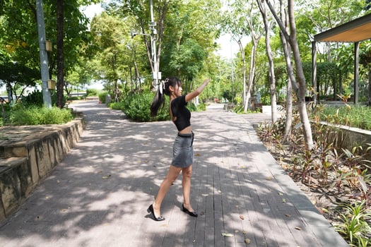 Asian woman dancing in the middle of a park photo