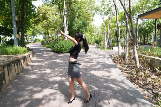Asian woman dancing in the middle of a park photo