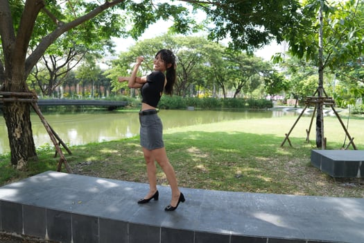 Asian woman dancing in the middle of a park photo