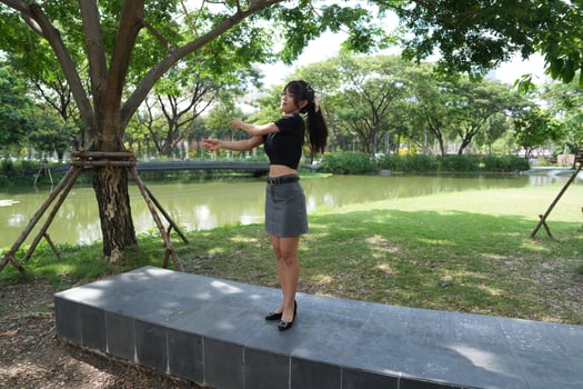 Asian woman dancing in the middle of a park photo