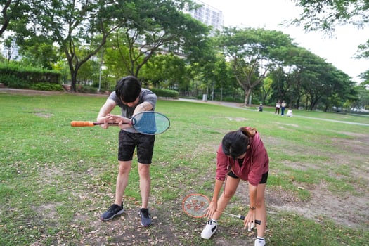 Young people play badminton and repair diligently in the park area. photo