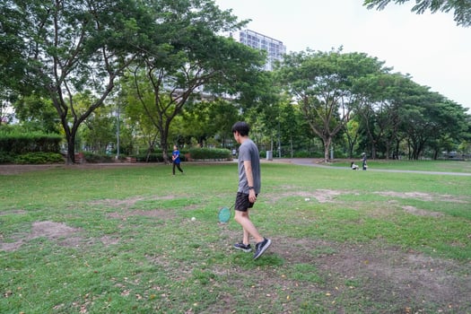 Young people play badminton and repair diligently in the park area. photo