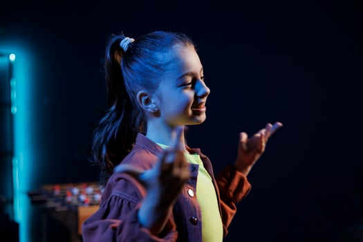 Close up shot of kid in dimly lit personal studio joins viral dance craze, recording family friendly for children audience. Little girl does latest internet dancing challenge late at night photo
