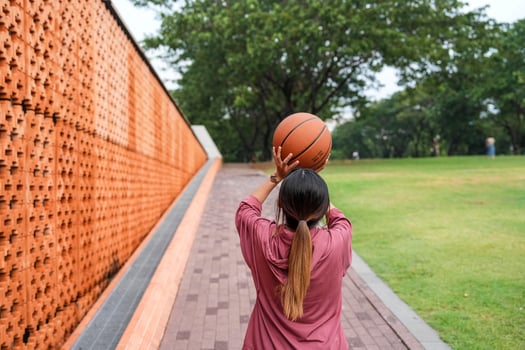 A woman plays basketball alone in a public section. photo