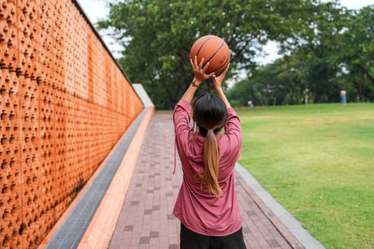 A woman plays basketball alone in a public section. photo