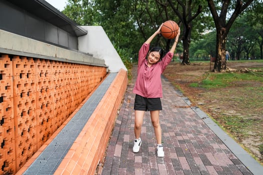 A woman plays basketball alone in a public section. photo