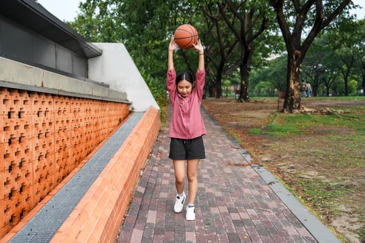 A woman plays basketball alone in a public section. photo