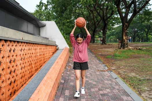 A woman plays basketball alone in a public section. photo