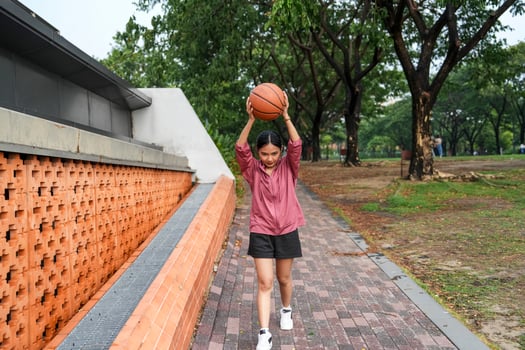 A woman plays basketball alone in a public section. photo