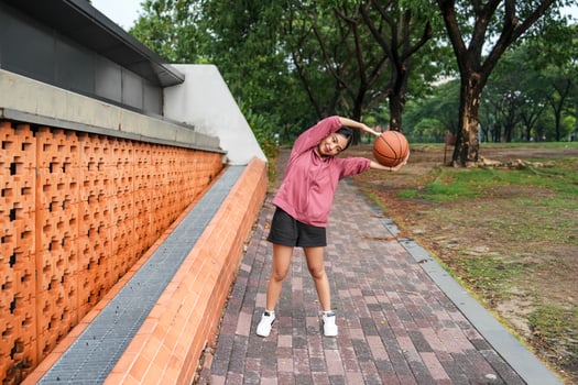 A woman plays basketball alone in a public section. photo