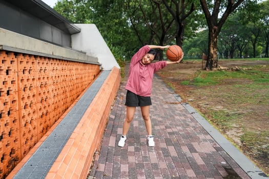 A woman plays basketball alone in a public section. photo