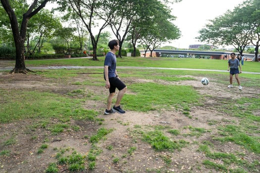 Asian man and woman are kicking and warming up before playing in soccer at outdoor park. photo