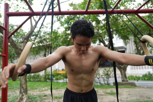 Asian man practicing gymnastics, doing gymnastics bar and hoop exercises and stretching, resting for sports. photo